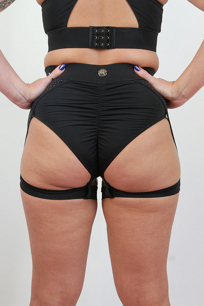 Person wearing black high-waisted shorts with a belt on a plain background